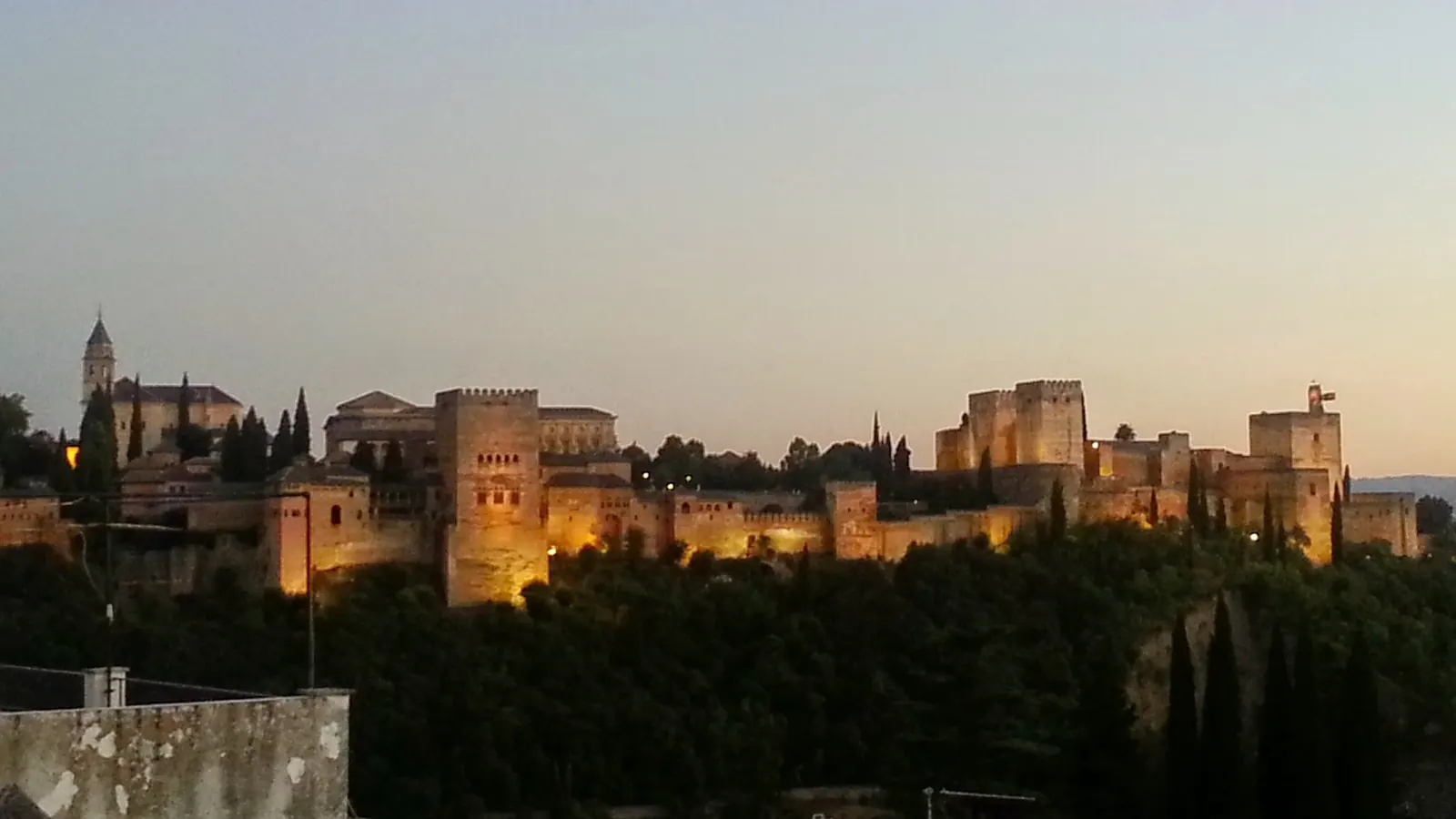 Alhambra osvětlená za soumraku, pohled ze svahu Sacromonte