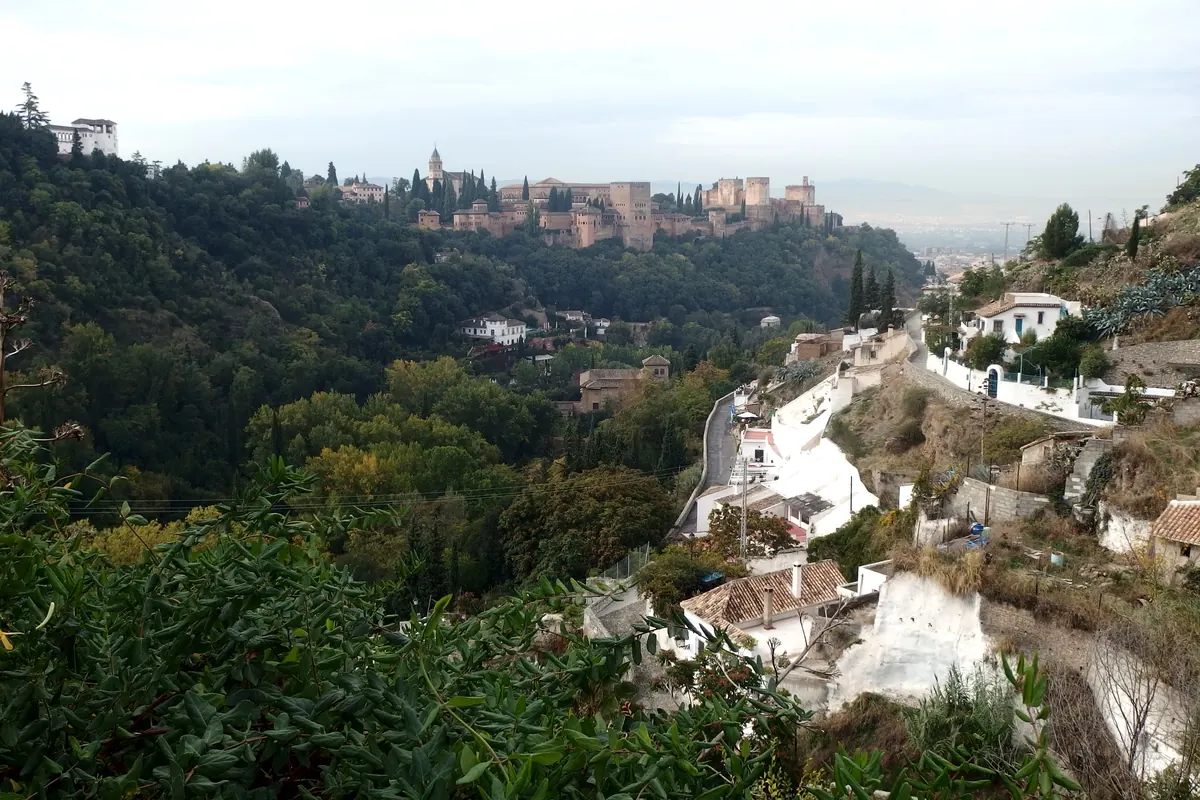 Hvidkalkede huleboliger på Sacromonte-skrenten med Alhambra på sin bakke på den anden side af dalen