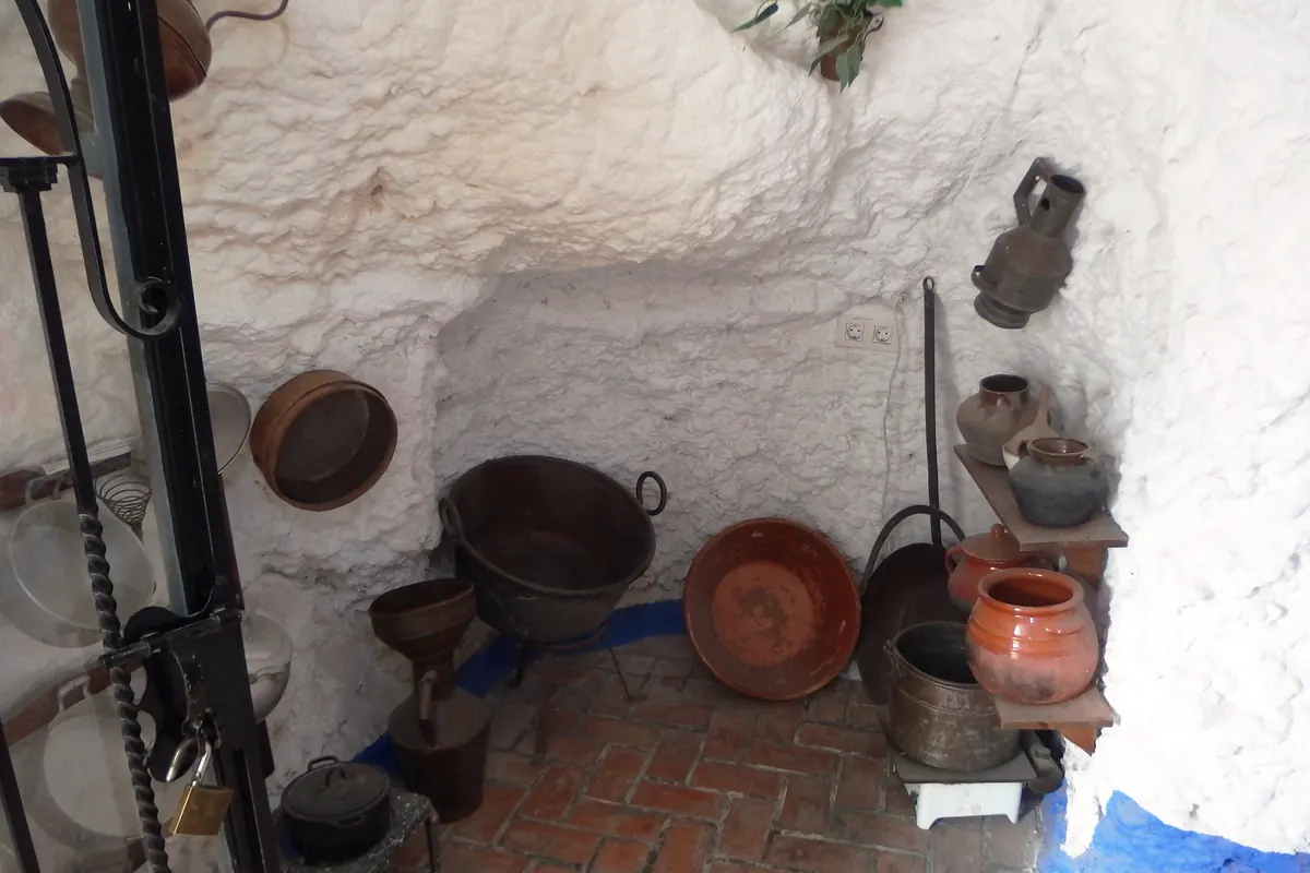 Et hvidkalket hulerum med kobbergryder og lerkrukker på Sacromonte-hulemuseet